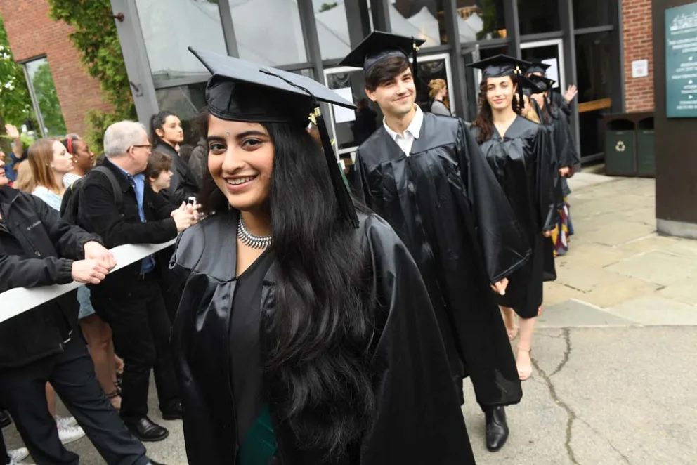 Graduates in caps and gowns smiling during a procession.