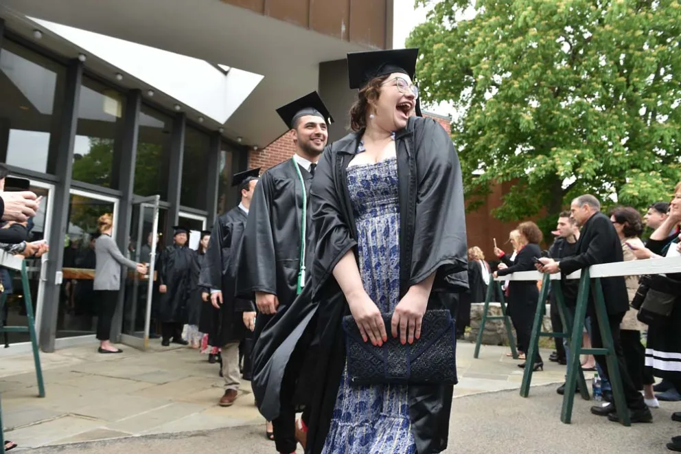 Individuals in graduation attire laughing joyfully at ceremony