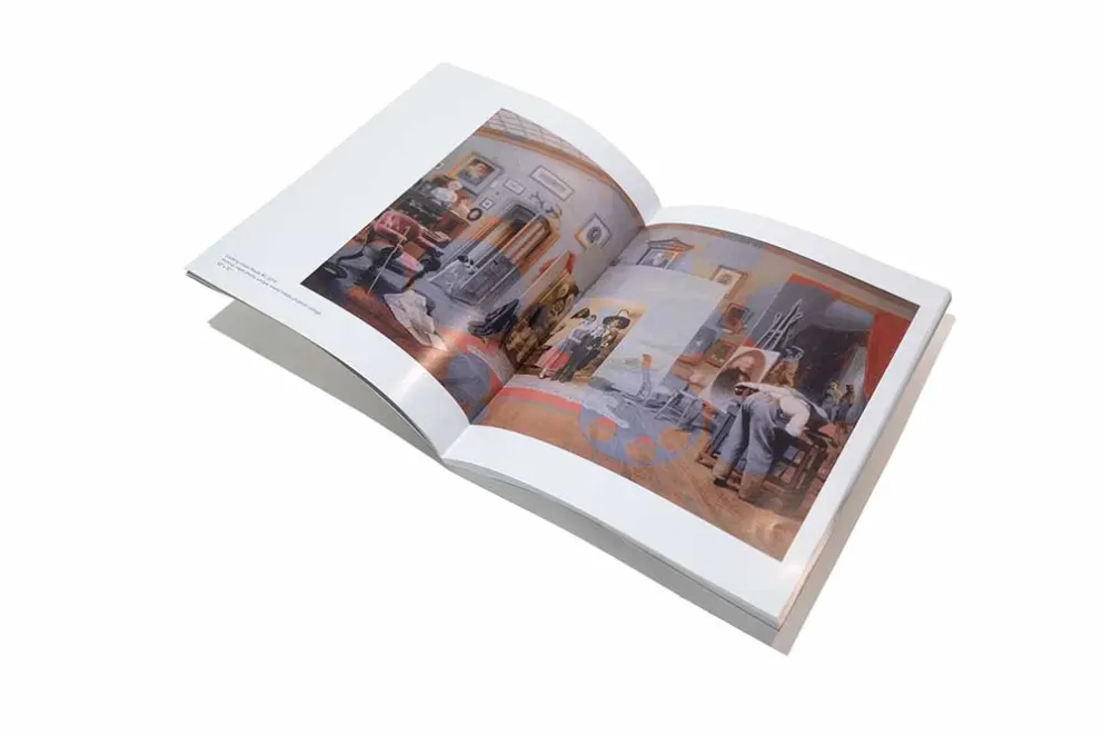 An open book with pages showing color photographs of an interior space, possibly from a magazine or art book, against a white background.