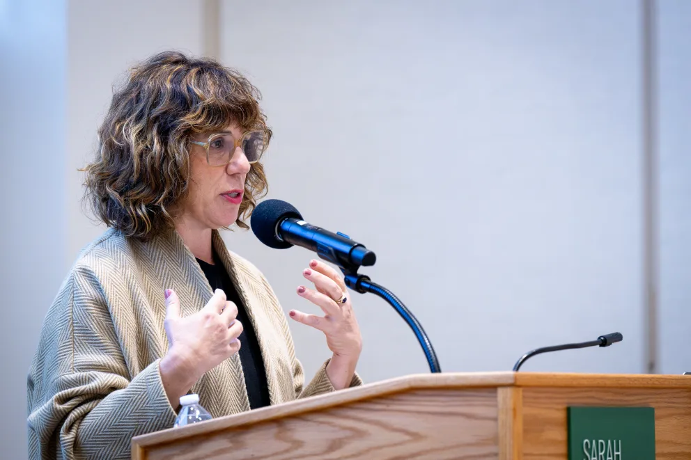 a woman standing at a podium with a microphone in front of her and a microphone in front of her