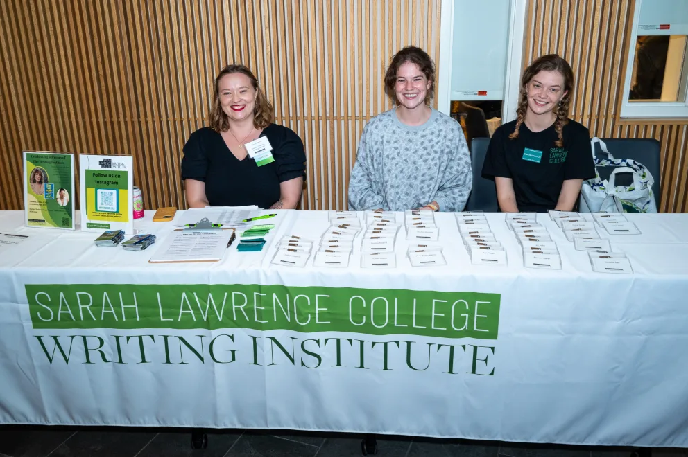 three women sitting at a table with a sign on it that says, sarah lawren college writing institute