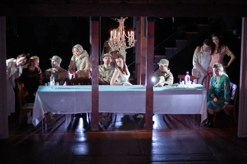 A group of people sitting at a table in front of a chandelier with candles on top of it.
