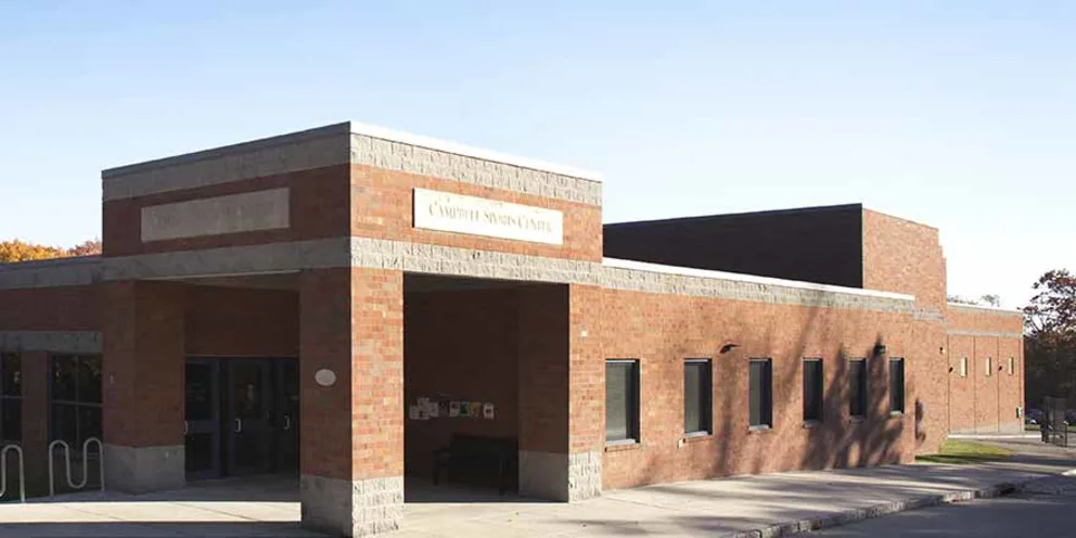 Brick building labeled "Camden Senior Center" in sunlight, with multiple windows and an entrance under a covered walkway.