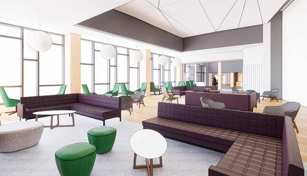 Modern lounge with large windows, dark sofas, green chairs, round white tables, and globe lights on the ceiling.
