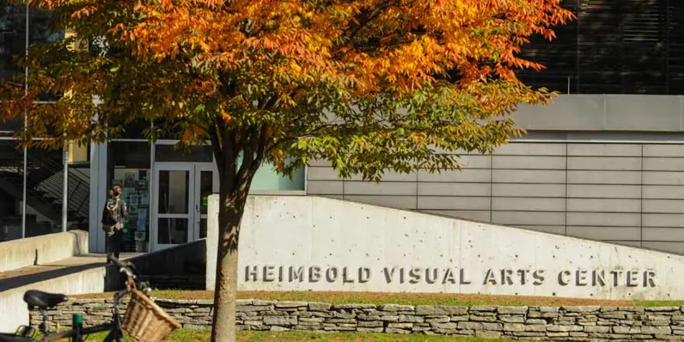 Entrance to Heimbold Visual Arts Center with fall foliage and a figure entering the building.
