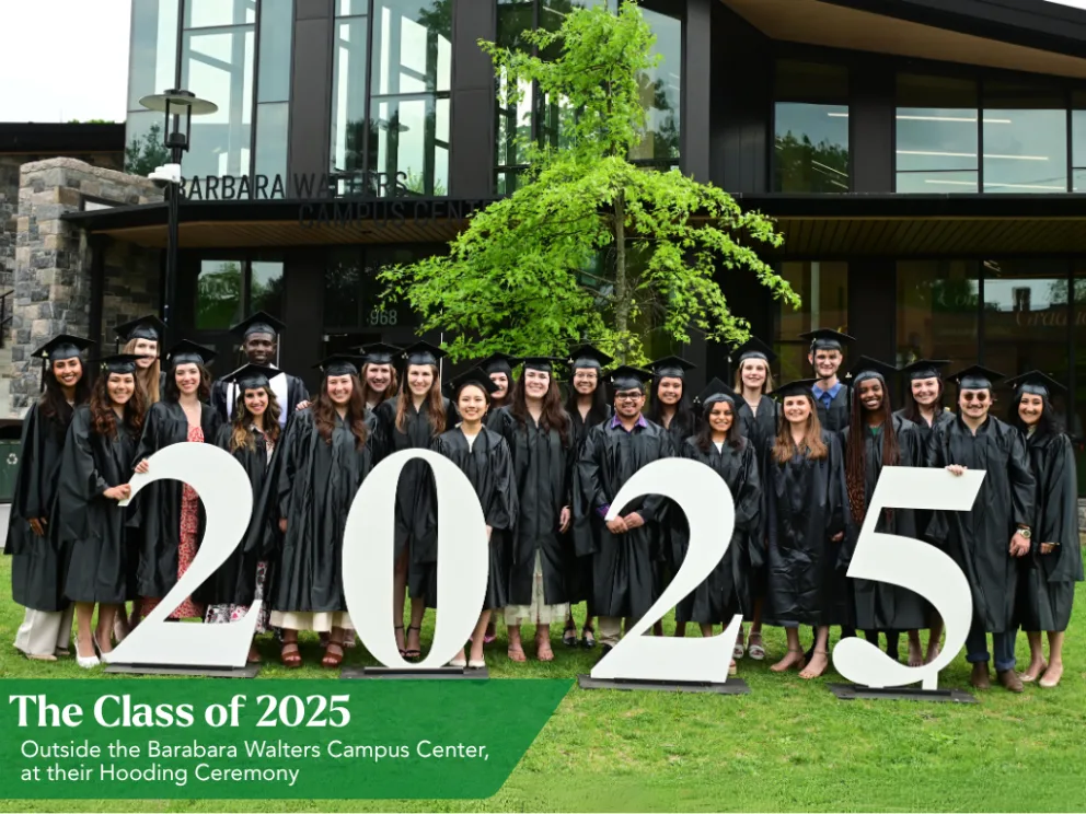 Graduates in black gowns and caps stand behind large "2025" numbers outside the Barabara Walters Campus Center.