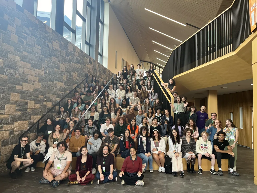 A large group of individuals posing on steps inside a modern building.