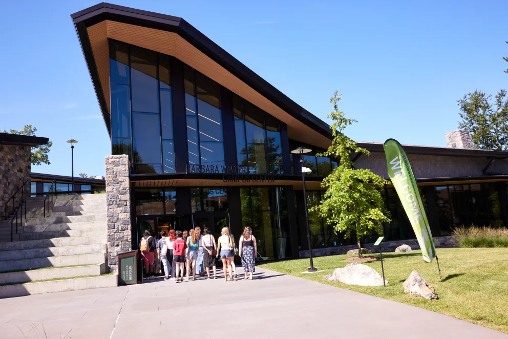 a group of people standing in front of a building with a large green sign on the side of it