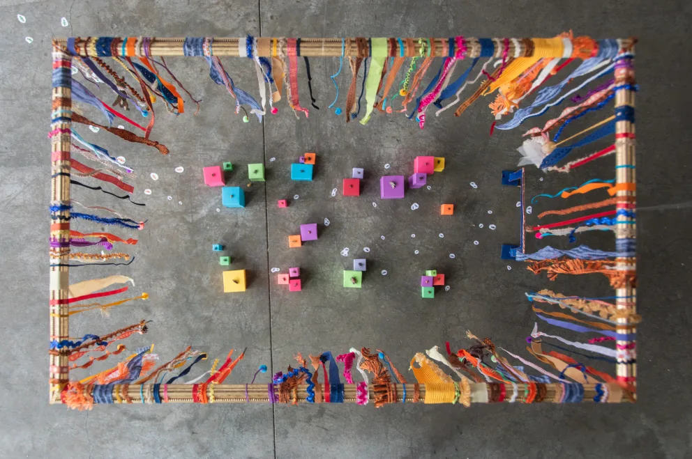 Colorful blocks and numbers inside a vibrant, fringed rectangular frame on a textured surface.