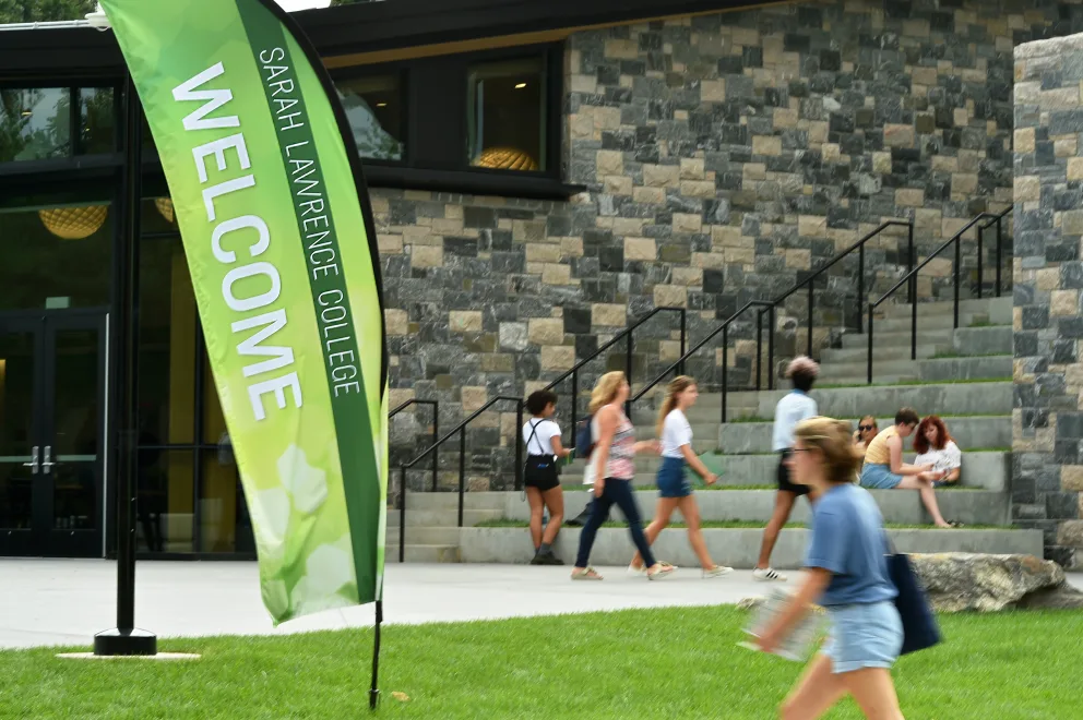 a group of people walking past a building with a welcome sign on the side of the building that says welcome
