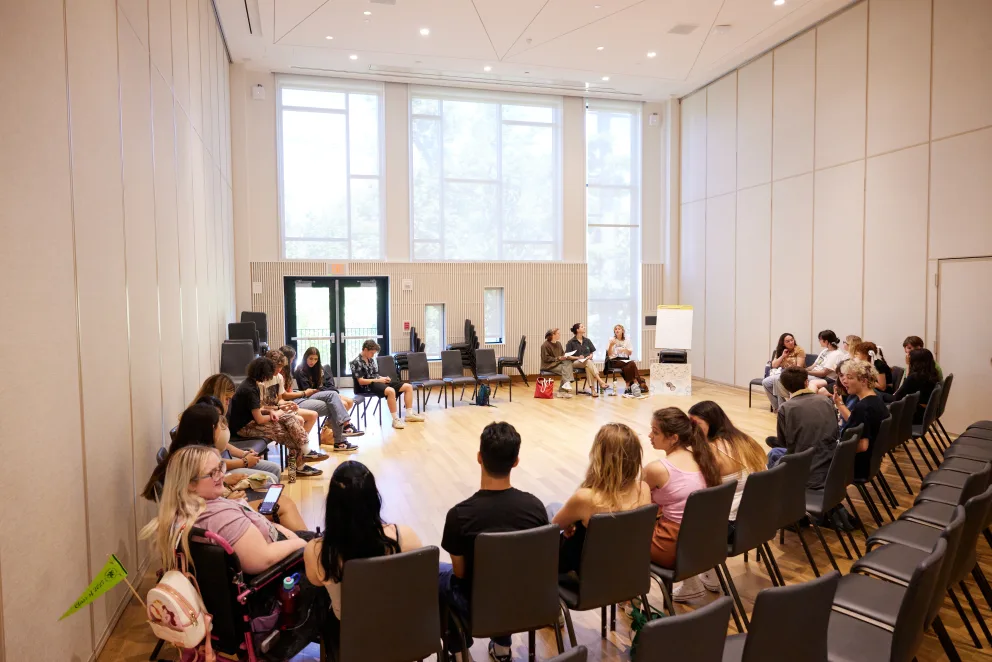 a group of people sitting in chairs in a room with a projector screen on the wall and a projector screen on the wall
