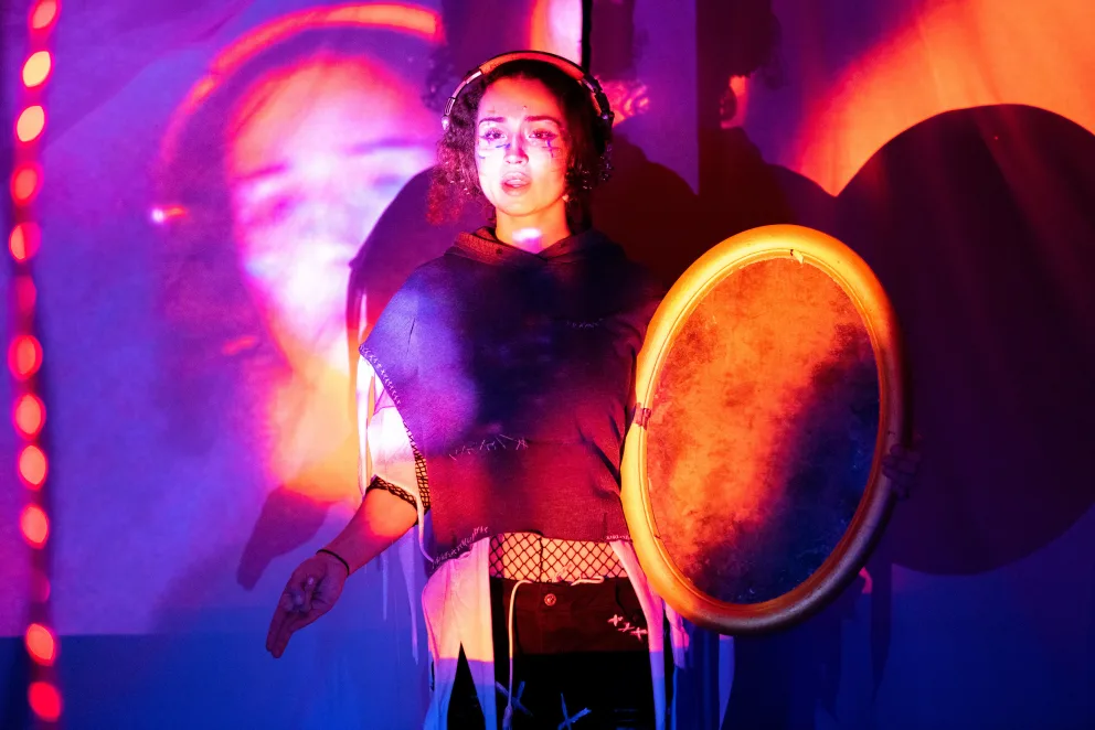 a woman holding a frisbee standing in front of a purple and blue background with lights on it