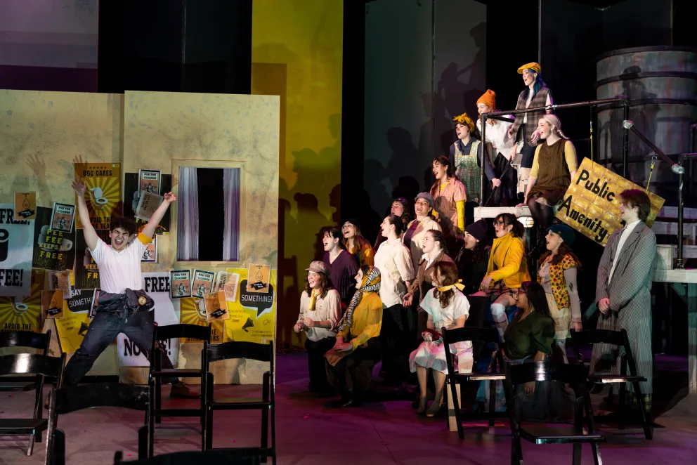 a group of people standing on top of a stage next to a group of people sitting on a chair