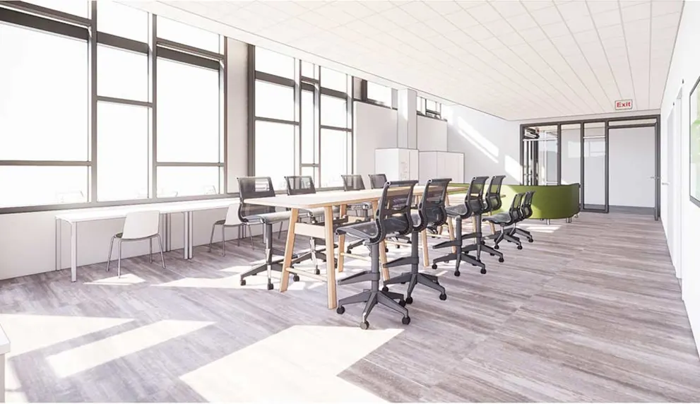 Bright, modern office with long table, black chairs, large windows, and wooden flooring. A green couch and exit sign are visible in the background.
