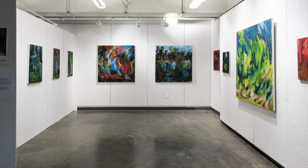 Gallery with abstract paintings featuring vibrant colors on white walls.