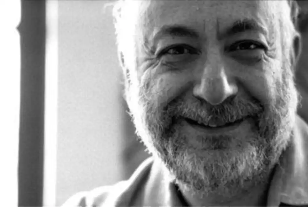 Smiling person with a beard in a black and white portrait.