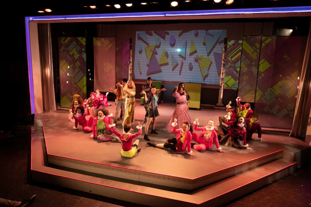 a group of people sitting on top of a wooden stage next to each other