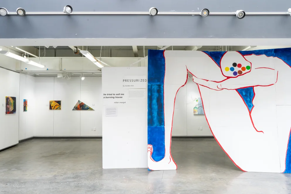 Art gallery with abstract paintings, including a large piece of a crouching figure outlined in red with multicolored dots on the head.