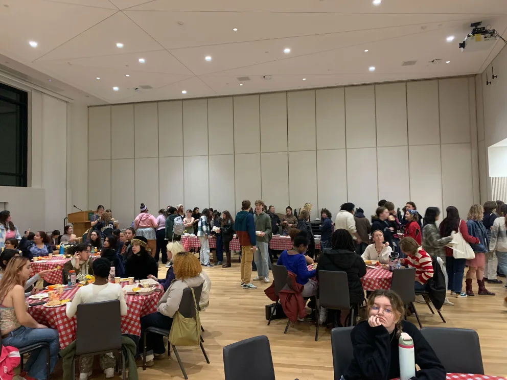 a large group of people sitting at tables in a room with red and white checkered tablecloths