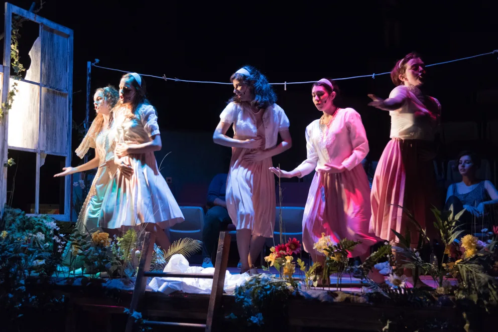 a group of people standing on top of a stage next to a wooden table with flowers on top of it