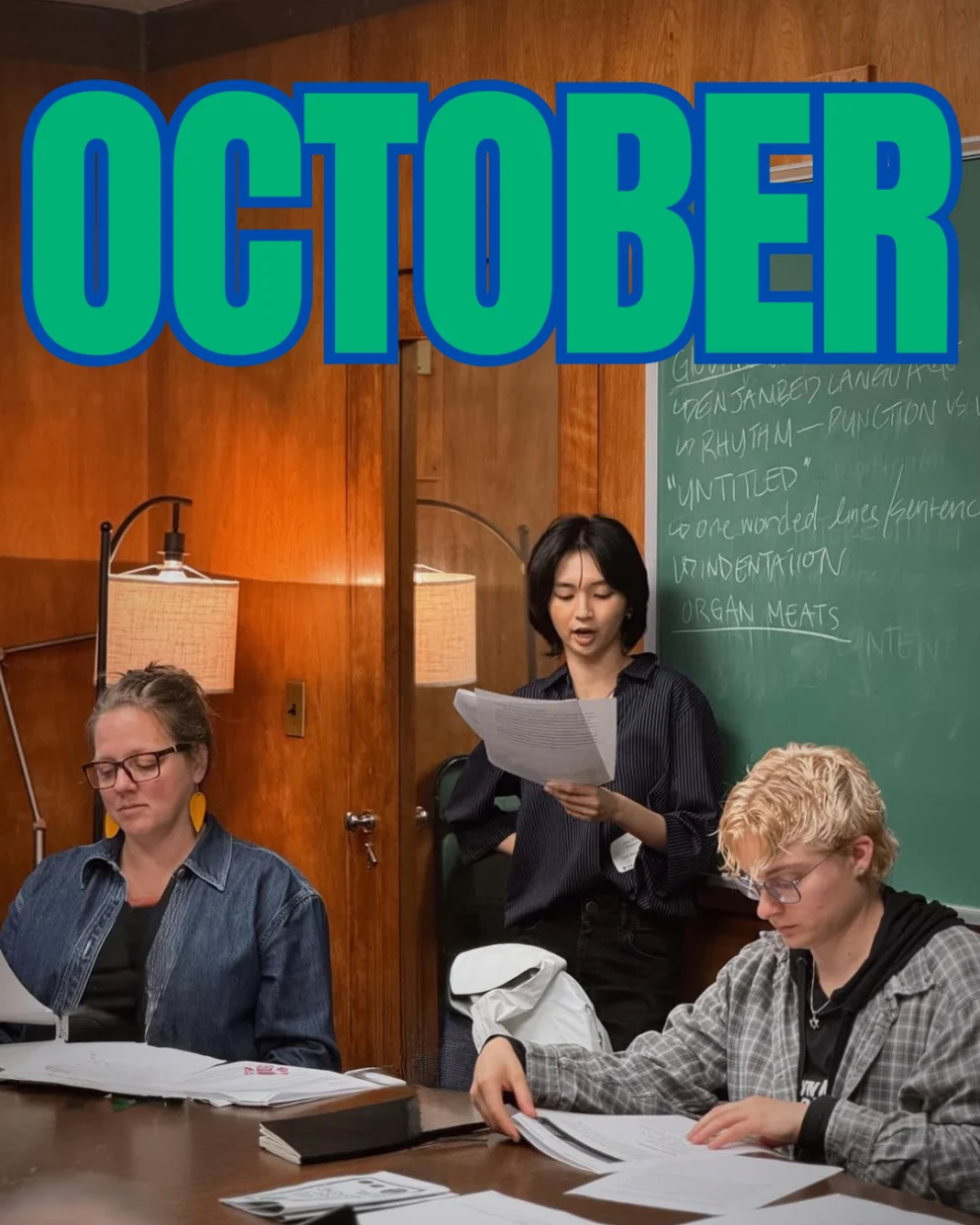 Three people read documents in a room with wood paneling and chalkboard. Large "OCTOBER" text is displayed above.