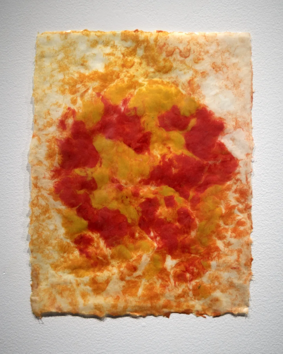 Abstract artwork on paper with swirling patterns of red, orange, and yellow. The colors blend together resembling fiery textures.