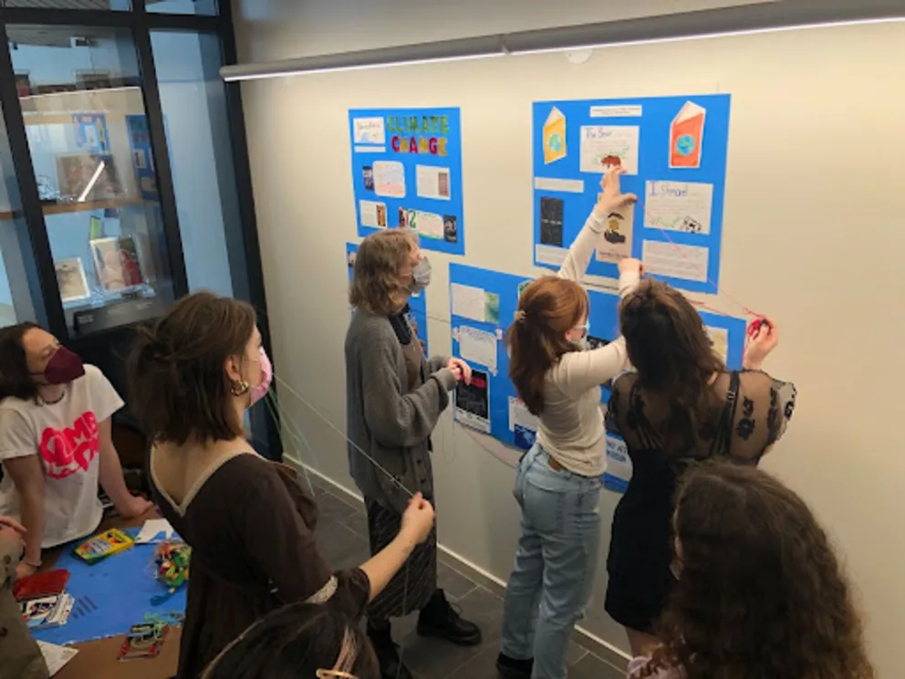 a group of people standing in front of a wall with posters on it and writing on the side of the wall