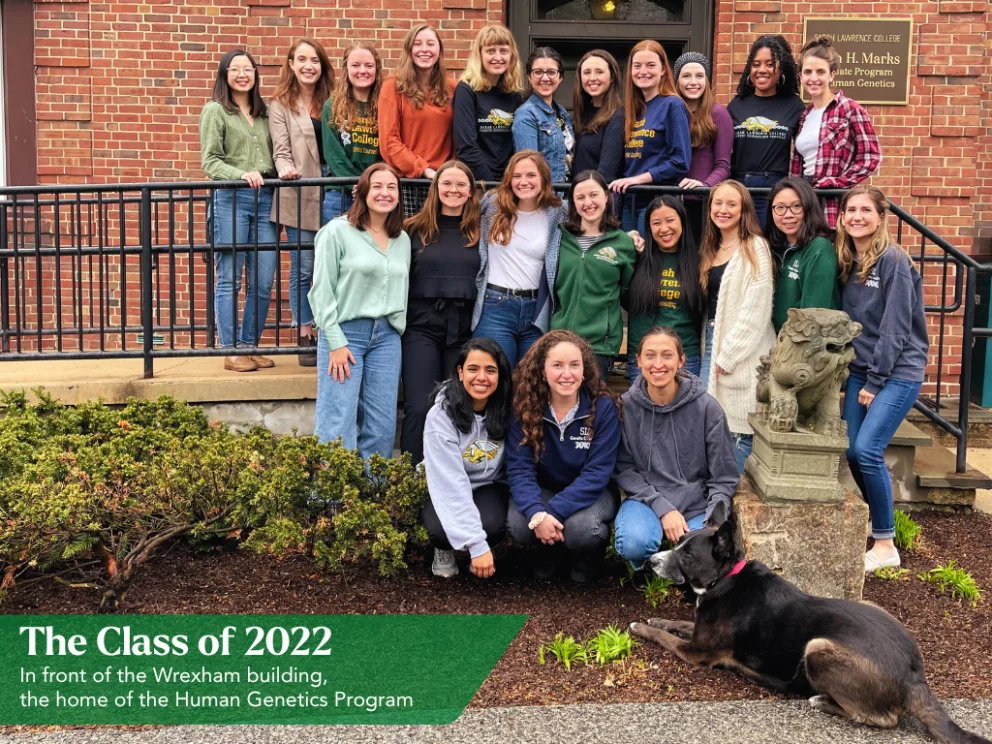 A group of people standing and kneeling in front of a brick building, with a dog lying on the ground in front. Sign reads "The Class of 2022."
