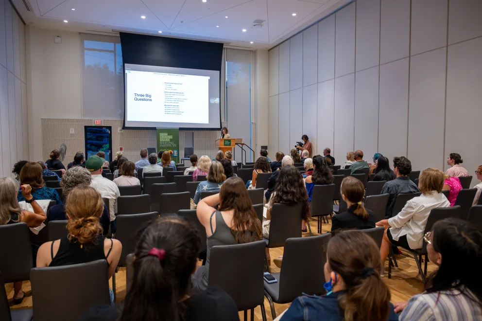 a group of people sitting in chairs in front of a projector screen with a presentation on the screen