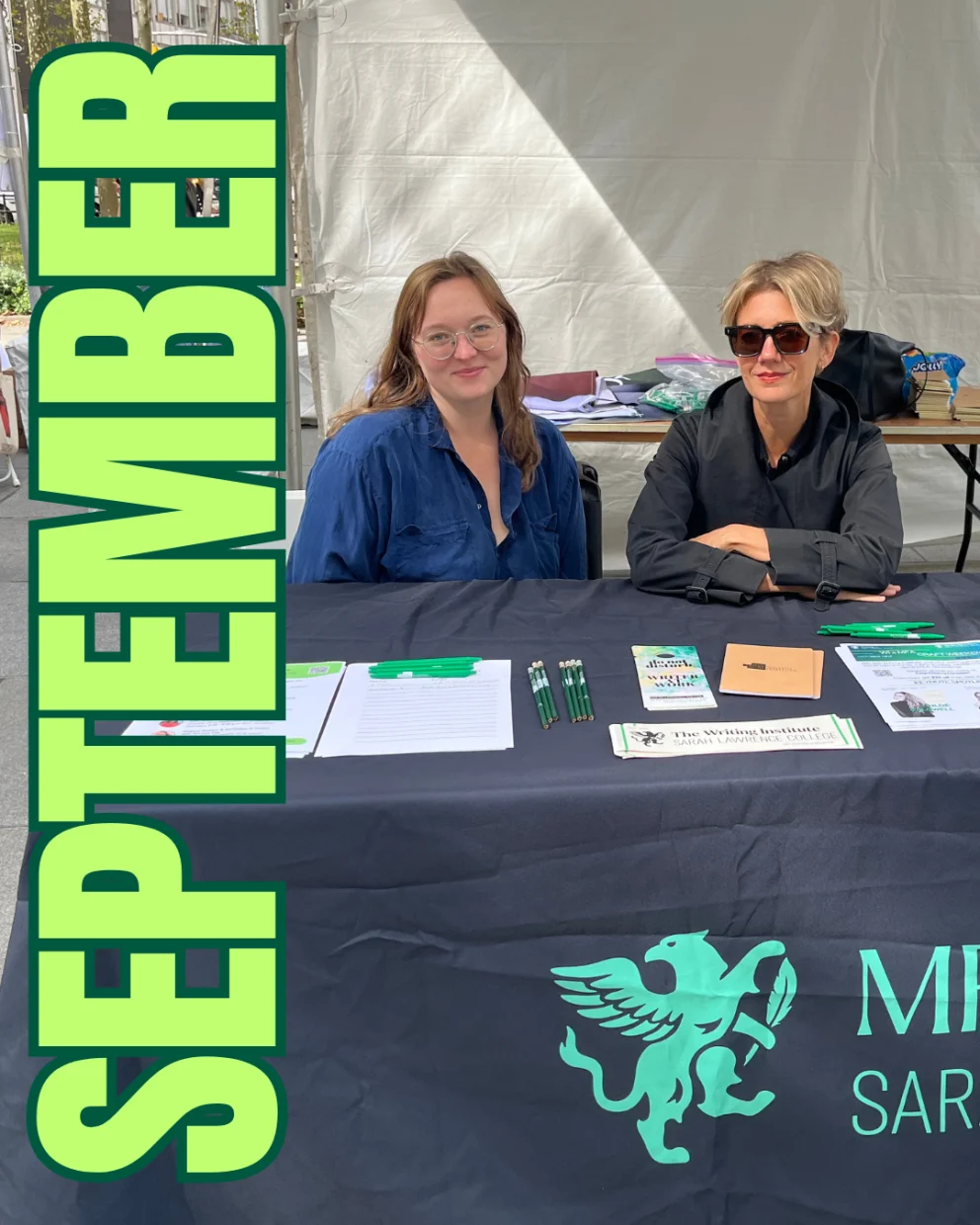 Two people sit at a table with brochures and pens under a tent. A large "September" is on the left.