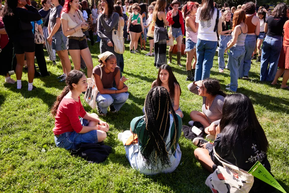 a group of people sitting on top of a lush green field next to each other on a sunny day