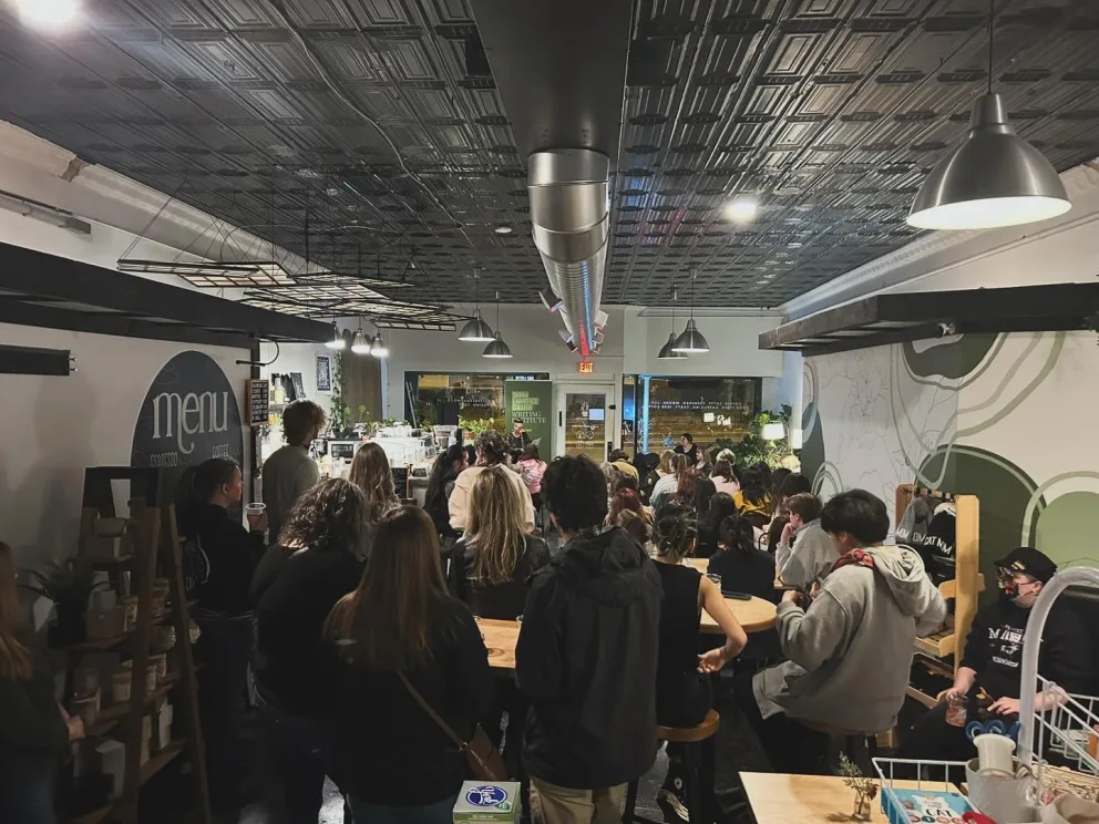 Crowded indoor space with individuals gathered, possibly an event, with a counter at the front.