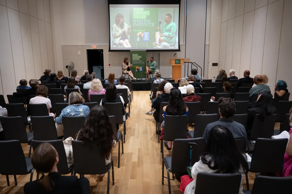 a group of people sitting in chairs in front of a projector screen in a room with a projector screen on the wall