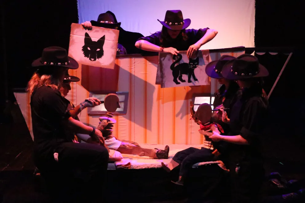 a group of people sitting on a stage with masks on their faces and a cat on a box behind them