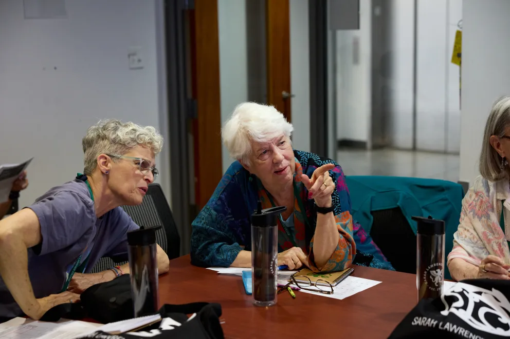 Two individuals engaged in discussion at a table with papers and water bottles.
