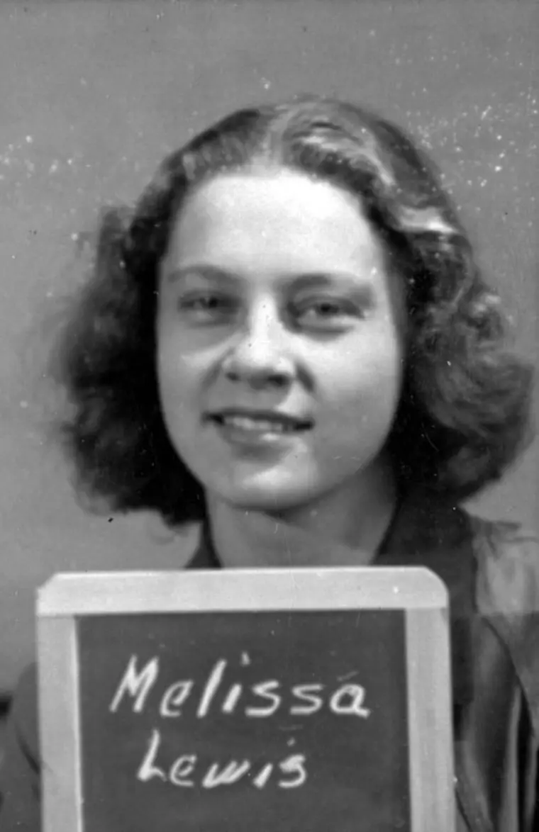 Vintage black and white photo of a person with a signboard displaying a name.