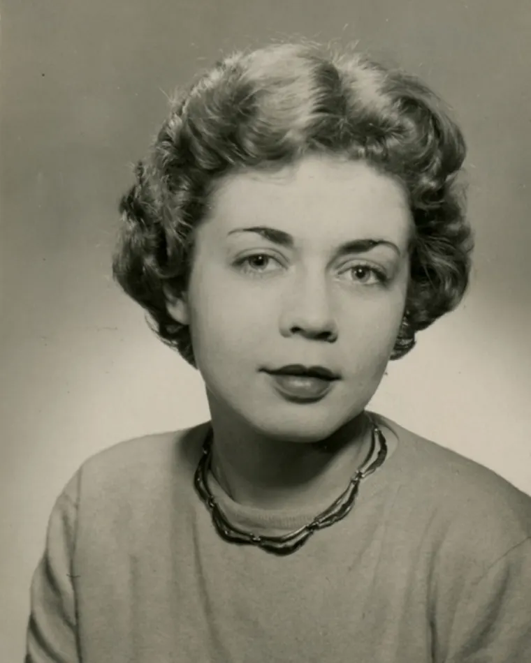 Vintage portrait of a person with curly hair and a necklace.