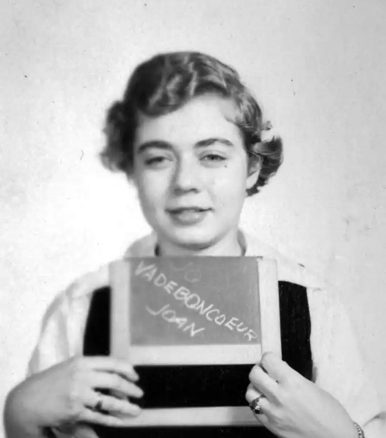 Person holding a chalkboard with handwriting on it.