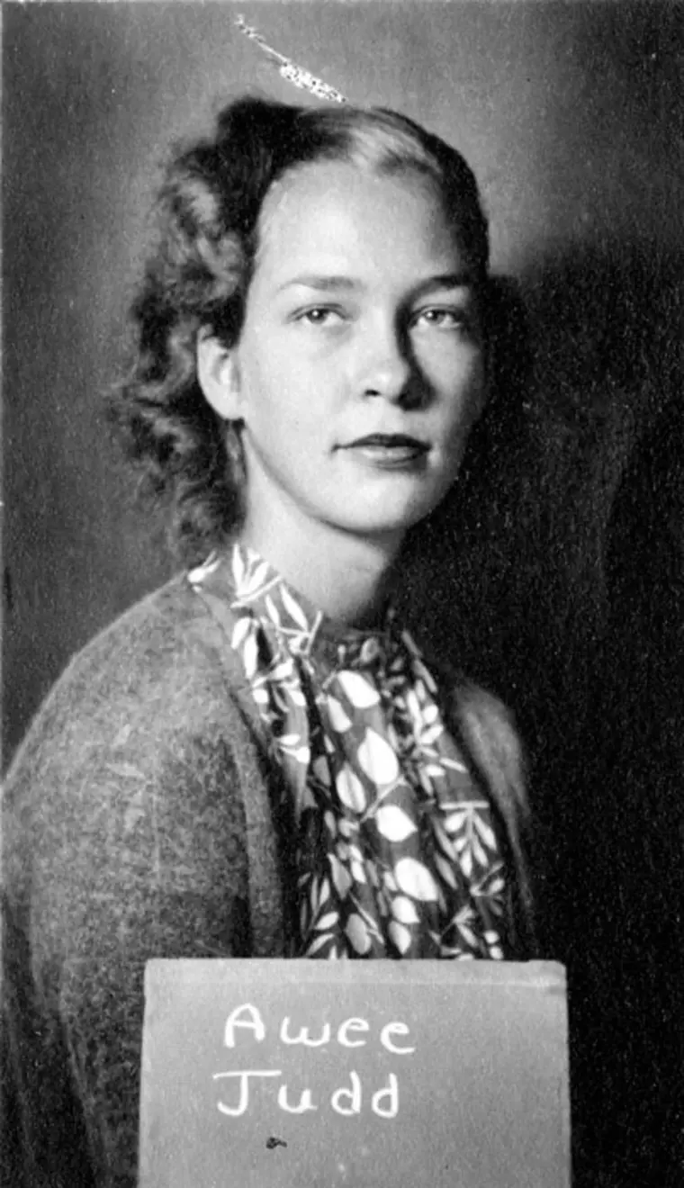 Vintage portrait of a person with a patterned scarf, holding a sign with a name.