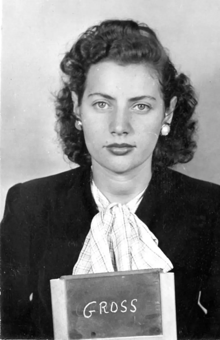 Vintage portrait of a person with curly hair, suit, and checkered tie holding a sign with "GROSS".