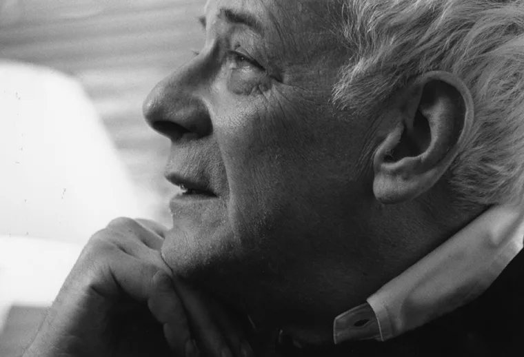 Profile of a person with light hair, gazing upward with a thoughtful expression, chin resting on hand.