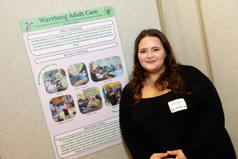Person smiling beside a presentation board titled "Wartburg Adult Care" with text and photos about care services and personal experiences.