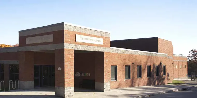 Brick building labeled "Camden Senior Center" in sunlight, with multiple windows and an entrance under a covered walkway.