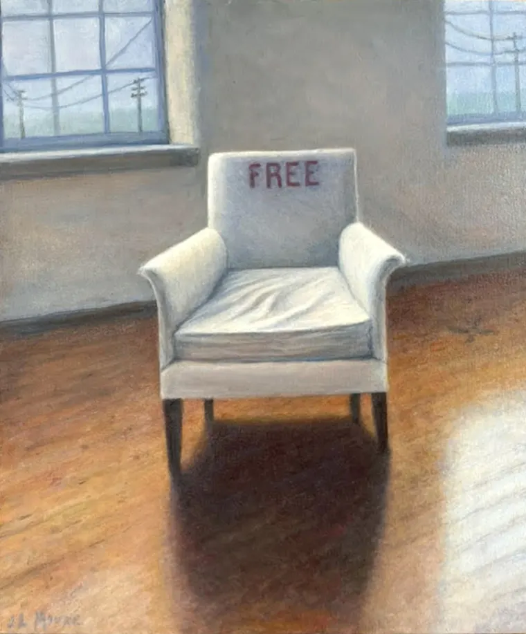 An empty armchair with the word "FREE" on it is placed in a sunlit room with wooden floors and large windows.