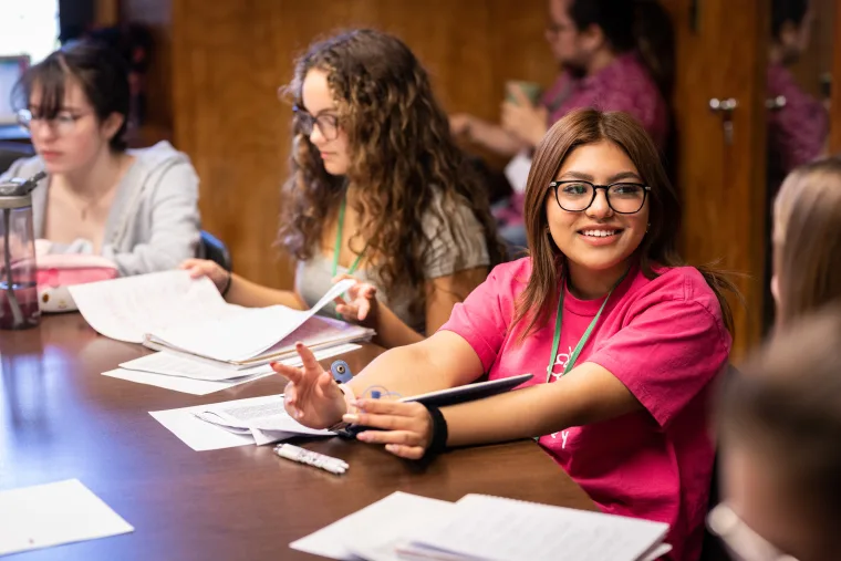 group of young students studying and talking at a conference table