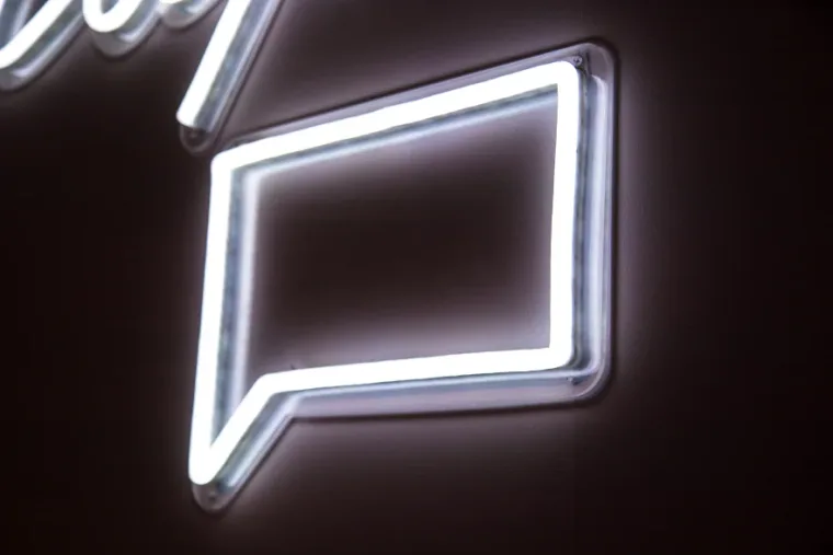 Bright neon speech bubble outline on a dark background.