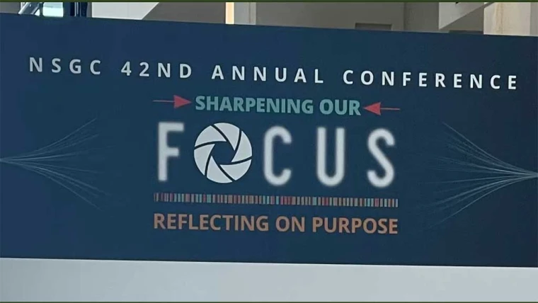 NSGC 42nd Annual Conference sign with the theme "Sharpening Our Focus, Reflecting on Purpose," featuring a camera lens graphic in "Focus."