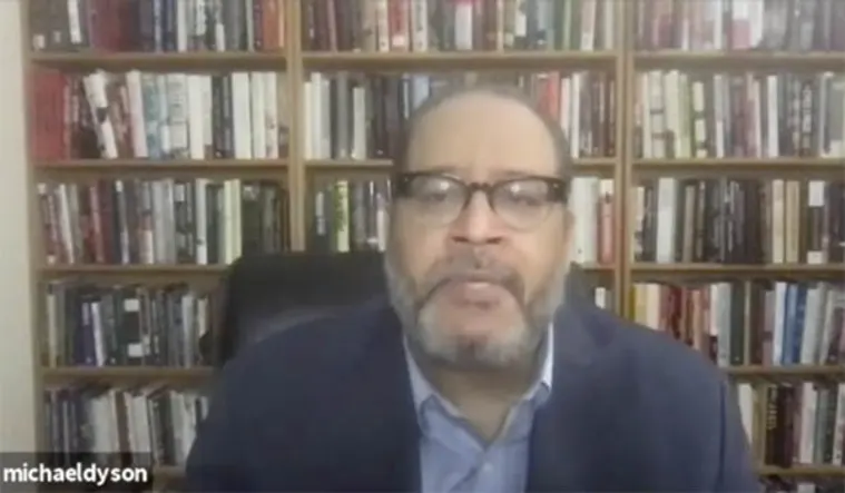 Person in glasses on a video call, seated in front of a large bookshelf filled with books. Username visible in the corner.
