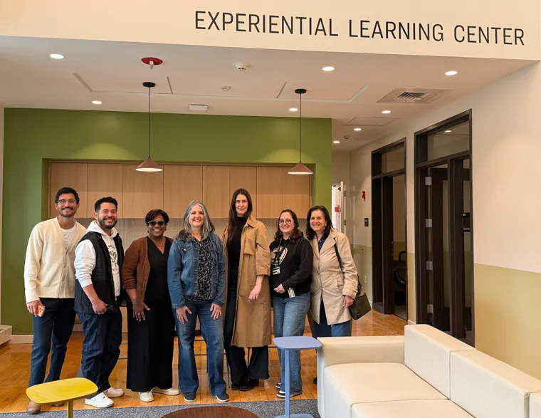 Seven individuals standing together in the Experiential Learning Center, smiling at the camera.