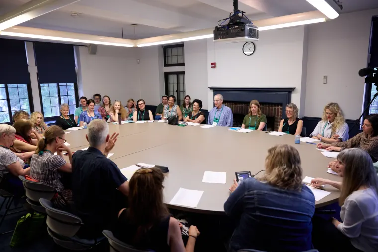 Group of individuals seated around a large conference table in a well-lit room.